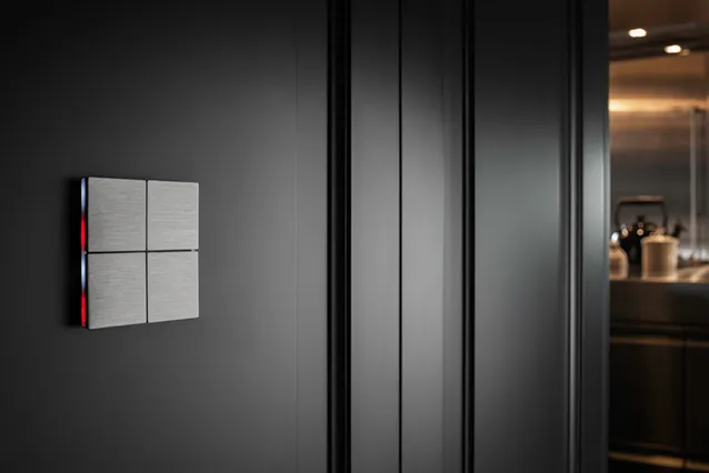Brushed-metal KNX keypad set flush into a dark panelled wall